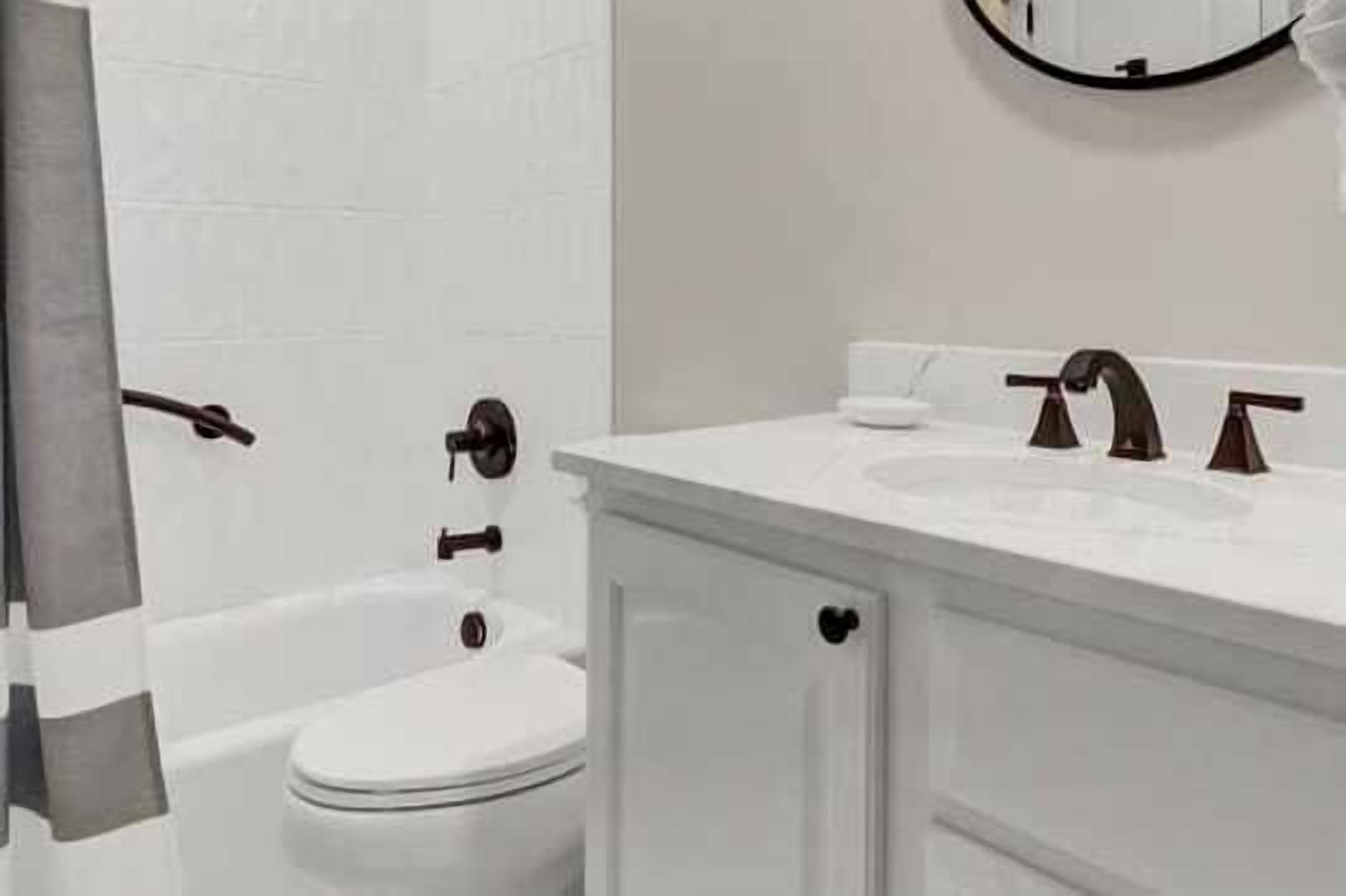 A bathroom with a white sink, two faucets, a toilet, and a bathtub.