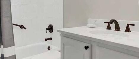 A bathroom with a white sink, two faucets, a toilet, and a bathtub.