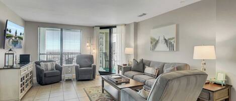 A modern living room with a sofa, armchairs, a coffee table, and a TV.