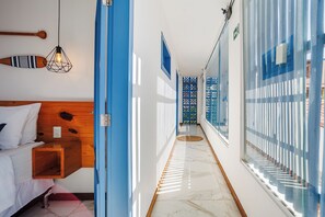 A hotel corridor with a wooden headboard bed, a hanging light fixture, and a patterned glass door. - Vila Maria Pousada (Jijoca de Jericoacoara)