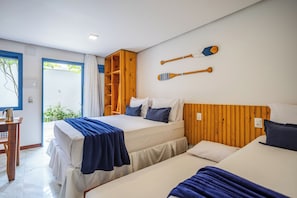 Habitación de hotel con dos camas, cabecero de madera, una mesita con hervidor y vista a zonas verdes.