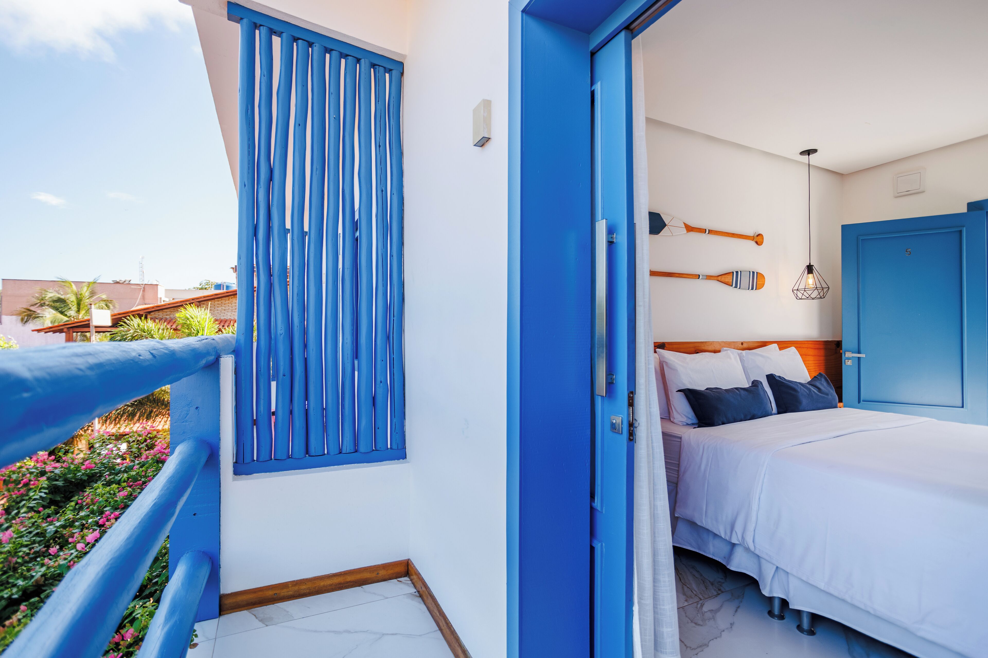 A bedroom with a bed, a door, and a window with blue shutters.
