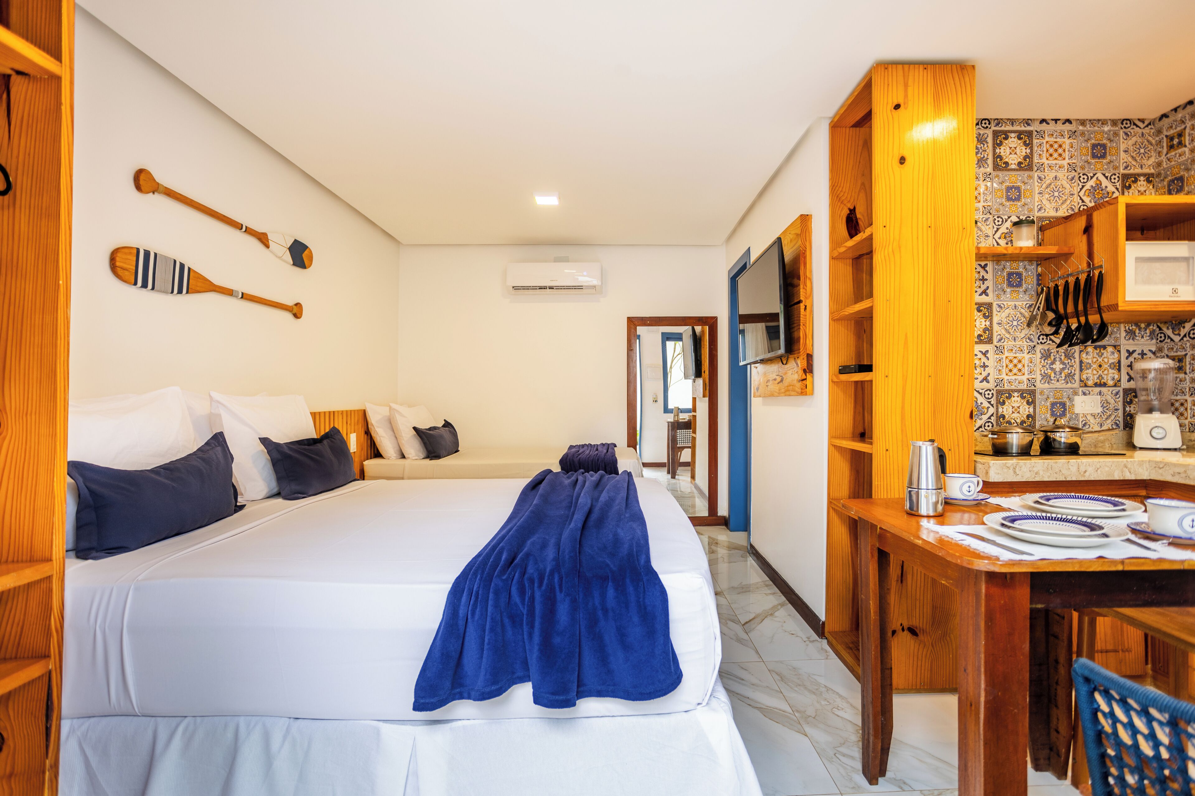 Habitación de hotel con cama, escritorio con cafetera y baño visible a través de una puerta abierta.