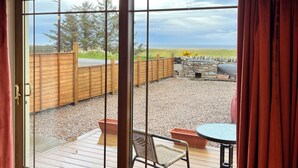 A room with a sliding glass door leading to an outdoor deck with a table and chairs.