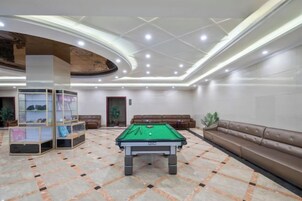 Una mesa de billar en una habitación con techo curvo e iluminación empotrada.