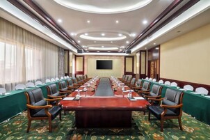 Un salón de conferencias con una larga mesa, sillas y una pantalla grande.