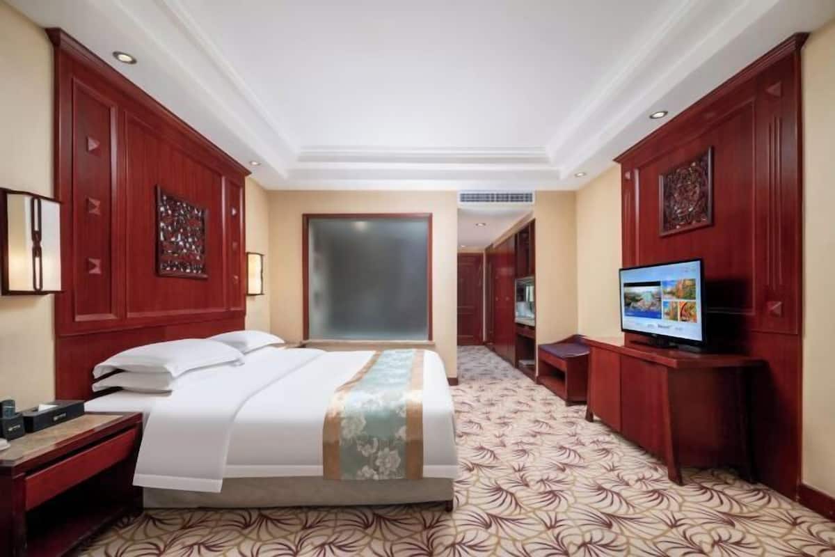A hotel room with a bed, television, and a desk.