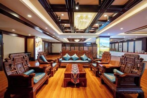 A spacious lobby with traditional wooden furniture, a central seating area, and a modern chandelier. - Kashi Laining Hotel (Kashgar City)