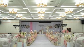 Un salón de banquetes con un pasillo central, candelabros y arreglos florales.