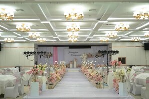 A banquet hall with a central aisle, chandeliers, and floral arrangements. - Kashi Laining Hotel (Kashgar City)