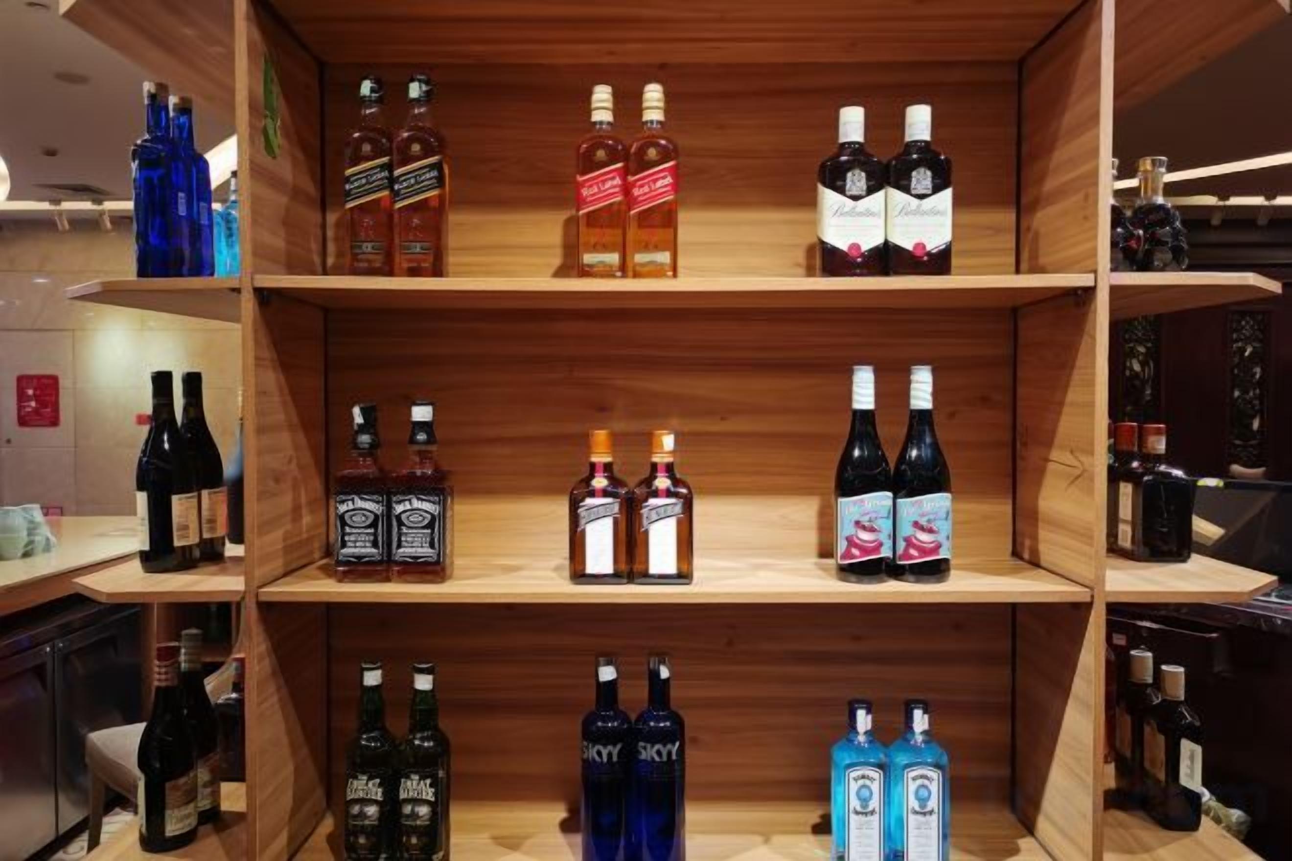 Una estantería de madera exhibe varias botellas de licores.