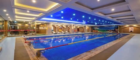 Una gran piscina interior con múltiples carriles, un techo con iluminación empotrada y vistas al área de la piscina.