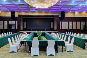 A conference room with long tables and white chairs, a large screen, and a stage. - Kashi Laining Hotel (Kashgar City)