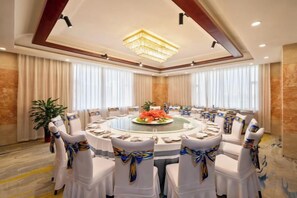 Una sala de conferencias con una mesa redonda, sillas blancas y una araña.