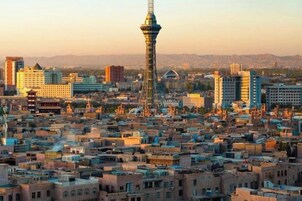 Un paisaje urbano con una torre destacada y edificios urbanos densos.