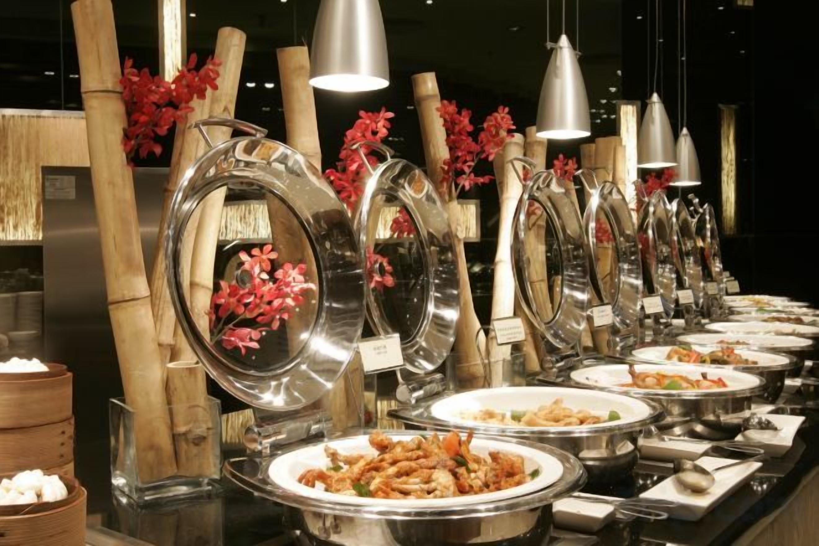Un aparador tipus buffet amb diverses zones de servei, cadascuna amb un bol metàl·lic gran i una etiqueta.