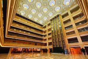 A multi-level atrium with a grand staircase, multiple floors, and a reflective floor. - Kashi Laining Hotel (Kashgar City)