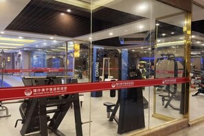 A gym with exercise equipment, glass walls, and a red barrier. - Kashi Laining Hotel (Kashgar City)