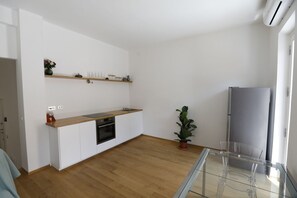 A modern kitchen with white cabinets, a wooden countertop, a built-in oven, and a refrigerator.