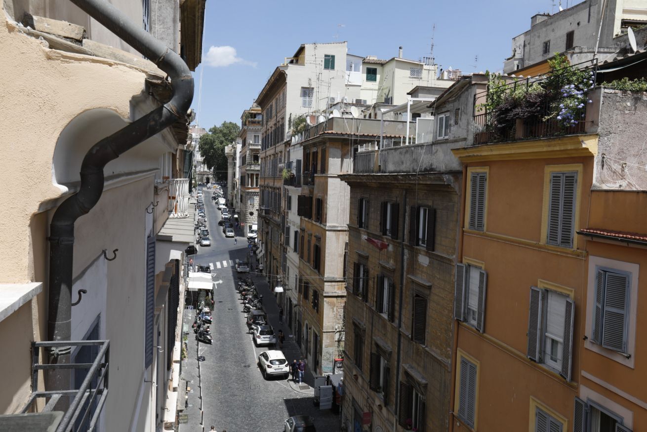 Una stretta via fiancheggiata da edifici a più piani, alcuni con balconi e persiane.