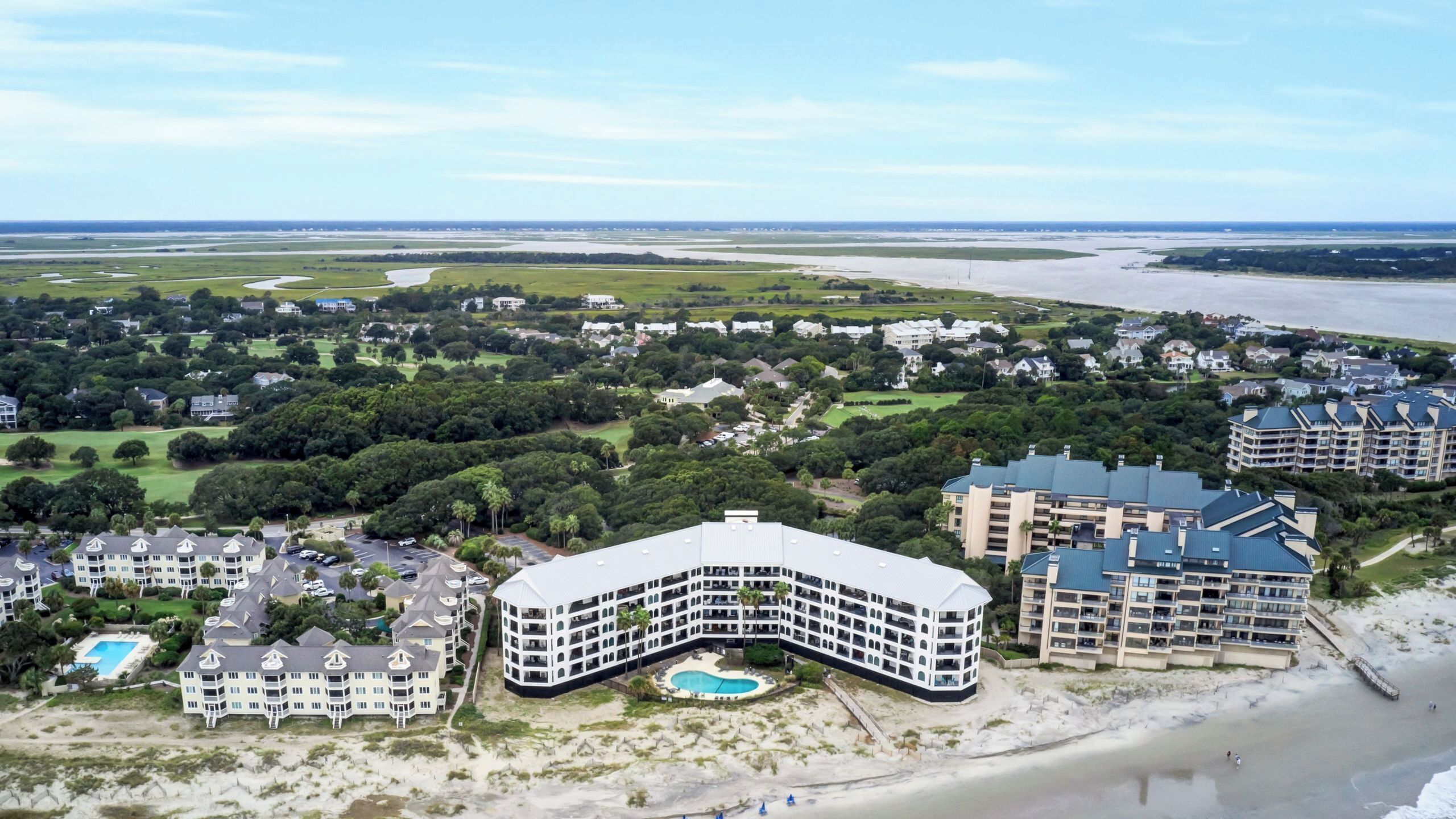 A coastal hotel with a pool, beachfront, and multiple buildings.