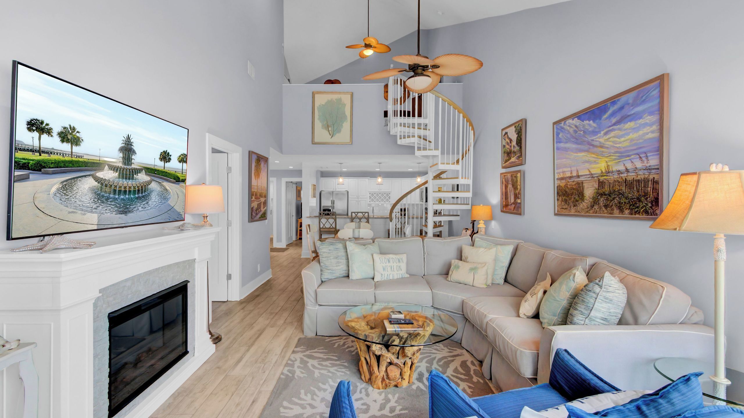 A living room with a fireplace, a television, a staircase, and a dining area.