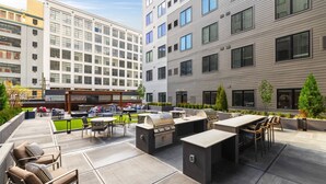 An outdoor patio area with seating, a barbecue station, and a TV screen.