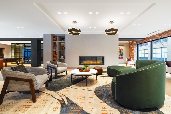 Un salon moderne doté d’une cheminée, de sièges confortables et d’une grande fenêtre.