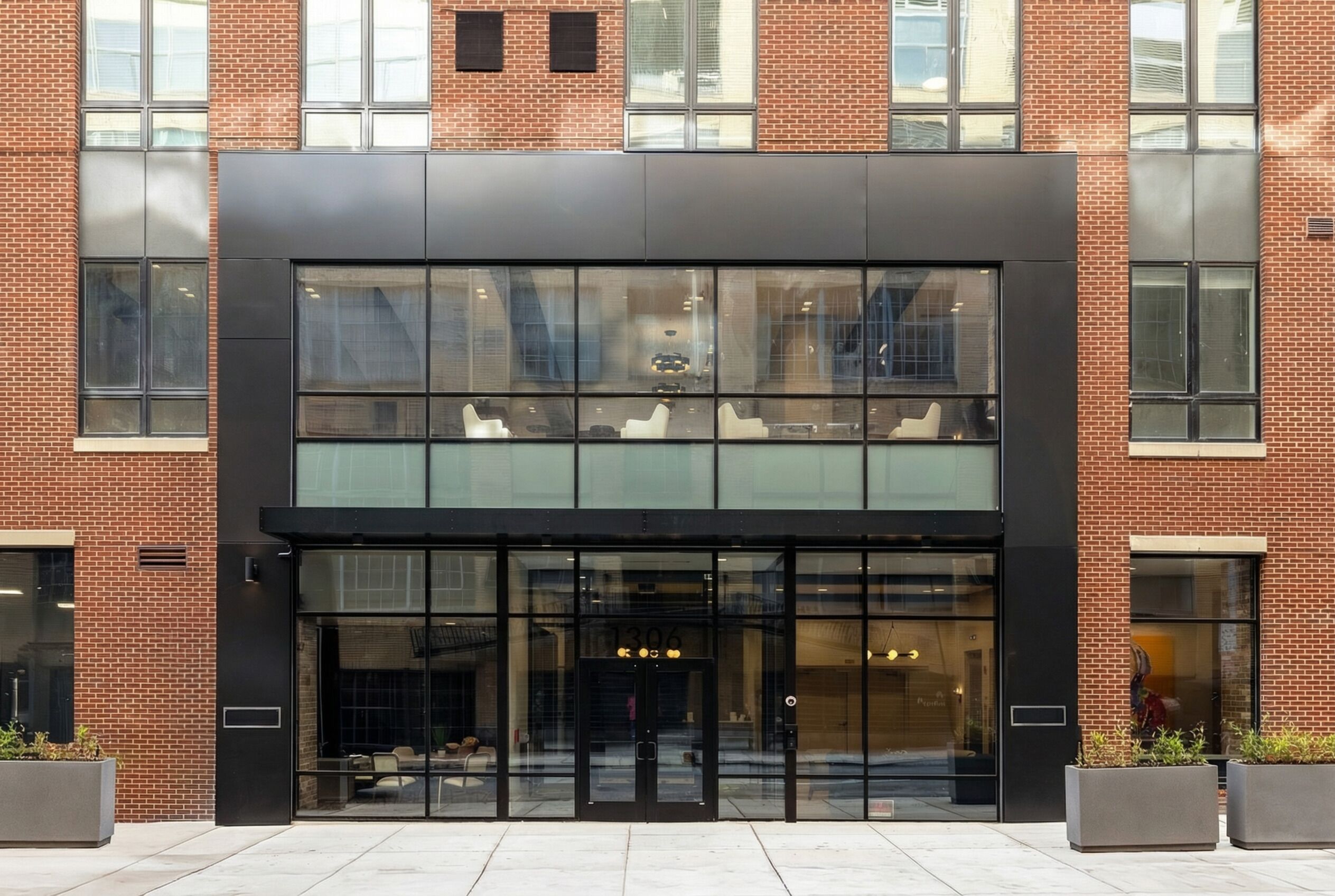 A modern building with a glass facade, a black entrance, and a brick exterior.
