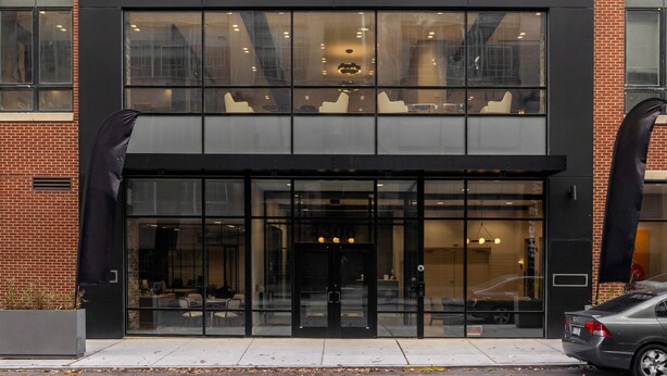 A modern building with a glass facade, large windows, and a black entrance.