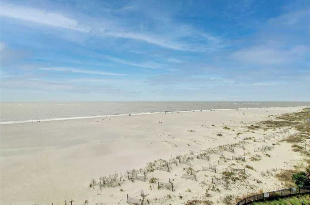 Una playa con una cerca y vegetación escasa.