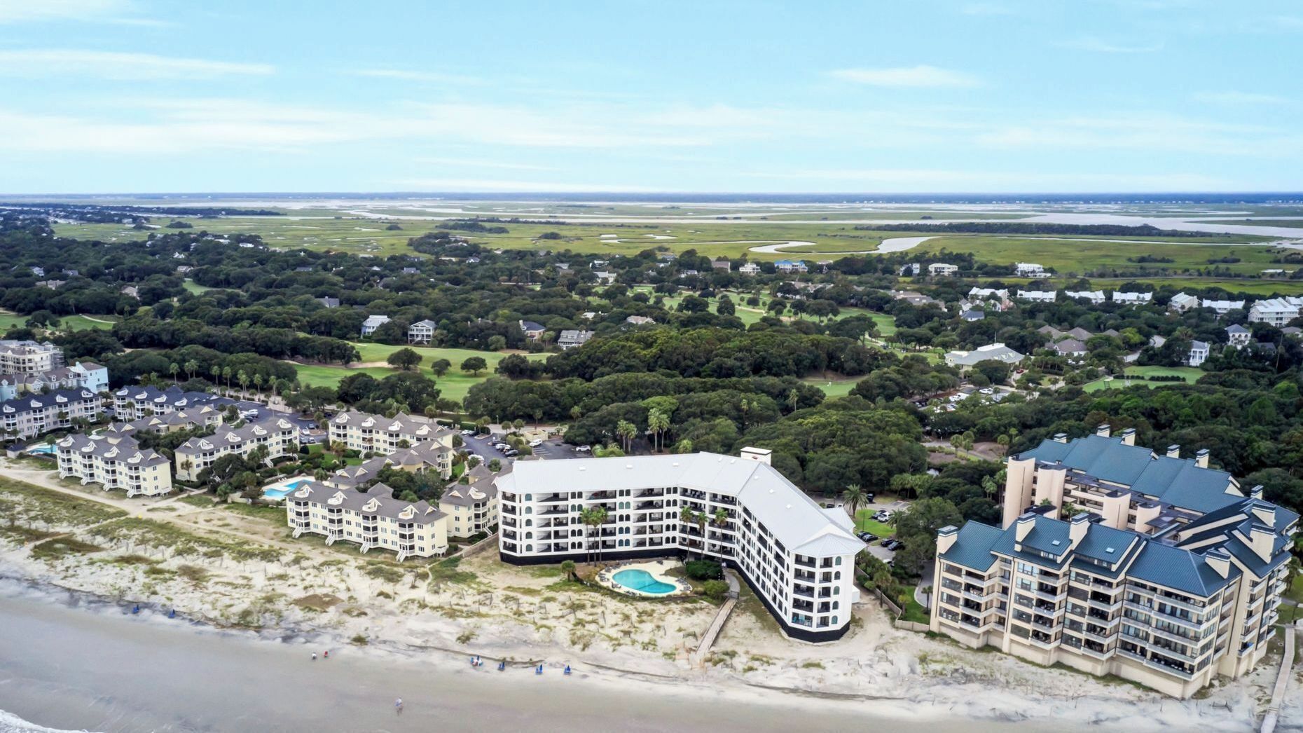 A coastal hotel with a pool, beachfront, and multiple buildings.