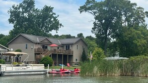 Une maison avec un quai, un bateau et un petit bateau amarré au quai.