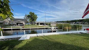 Un quartier résidentiel avec une jetée qui s’avance sur une étendue d’eau calme, entouré de maisons et sous un ciel dégagé.