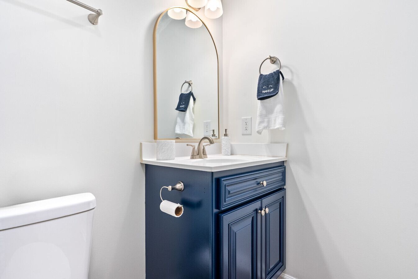 A bathroom with a white toilet, a sink with a mirror above it, and a towel hanging on a ring.