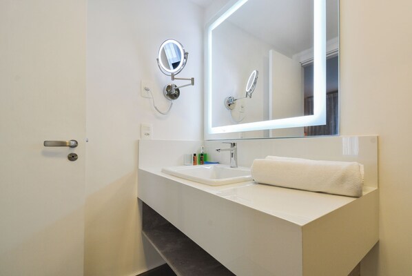 Une salle de bain moderne avec un lavabo blanc, un grand miroir et une serviette posée sur le comptoir.