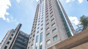 A modern high-rise building with a glass facade and a unique curved structure in the foreground. - Queen suite - Berrini (Cidade Monções São Paulo)