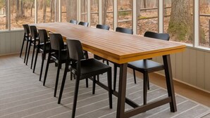 Une salle de conférence dotée d’une longue table et de chaises, de grandes fenêtres donnant sur une forêt et d’un plafond équipé d’un éclairage encastré.