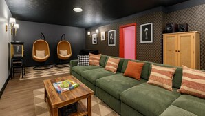 Un salon moderne avec un canapé vert, deux fauteuils en bois, une table basse et un tapis à motifs.