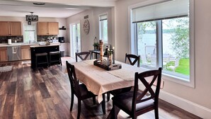 A spacious kitchen with wooden cabinets, a dining area with a table and chairs, and a large window offering a view of a lake.