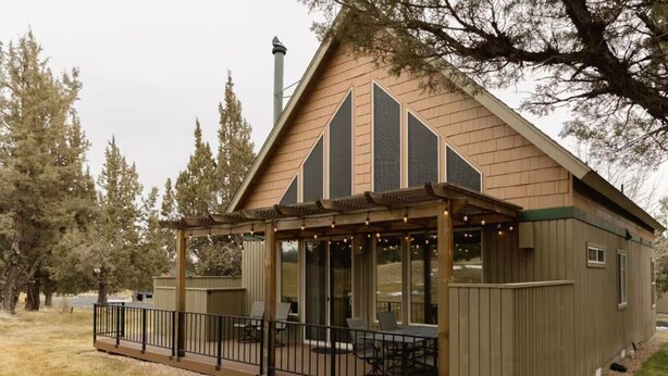 A small, single-story house with a covered patio area featuring outdoor furniture. - Luxury Chalet + Arcade  3BRD Dogs OK (Redmond)
