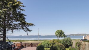 A wooden deck with a view of a lake and distant hills. - Fishers Cottage (Inverness)
