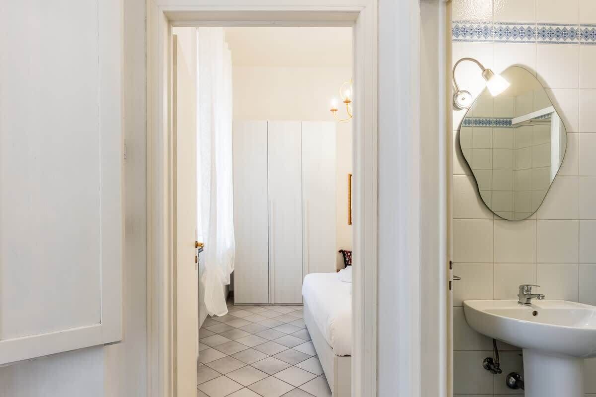Une salle de bain avec un lavabo blanc, un miroir et un espace douche.