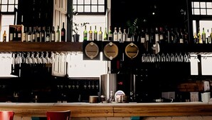 A bar area with a wooden counter, hanging wine glasses, and a variety of bottles. - Apartamento 3 Quartos 116m² no Batel Curitiba (Curitiba)