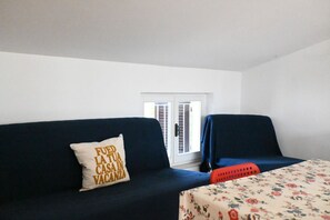 Une pièce avec un canapé bleu foncé, une nappe à motifs floraux et une fenêtre donnant sur un beau paysage.