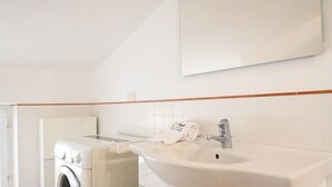 A bathroom with a washing machine, a sink, and a towel rack. - M437 – Marcelli, two-room apartment with air conditioning (Marcelli)