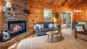 Ein gemütliches Blockhaushaus-Interieur mit Kamin, einer Couch, einem Couchtisch und einem Essbereich.