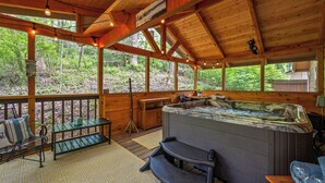 Eine Holzcabin mit Whirlpool, Sitzgelegenheit im Freien und Blick auf den Wald.