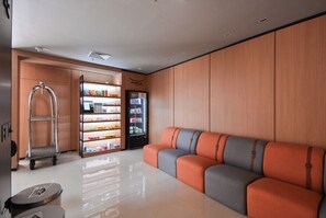 A modern lobby with a seating area, a vending machine, and a cart.