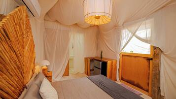 A bedroom with a bed, a bedside table, a lamp, and a wooden desk.